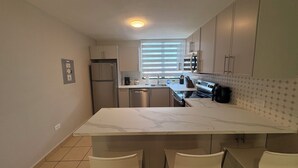 A modern kitchen with a marble countertop, stainless steel appliances, and a window with blinds. - Recently Renovated Marvelous 3-bedroom condo with AC in charming Aquatika, Loiza (Loiza)