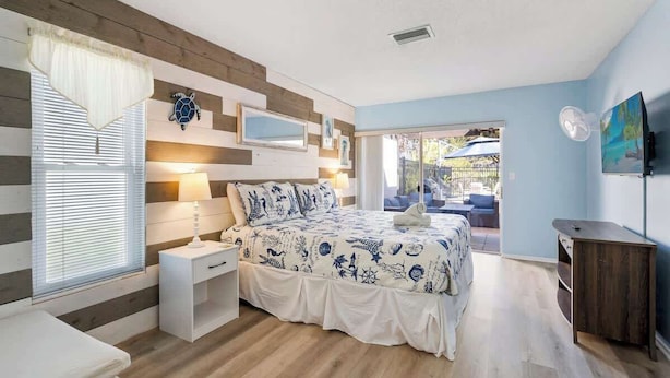 Un dormitorio con cama, mesita de noche y vistas al exterior.