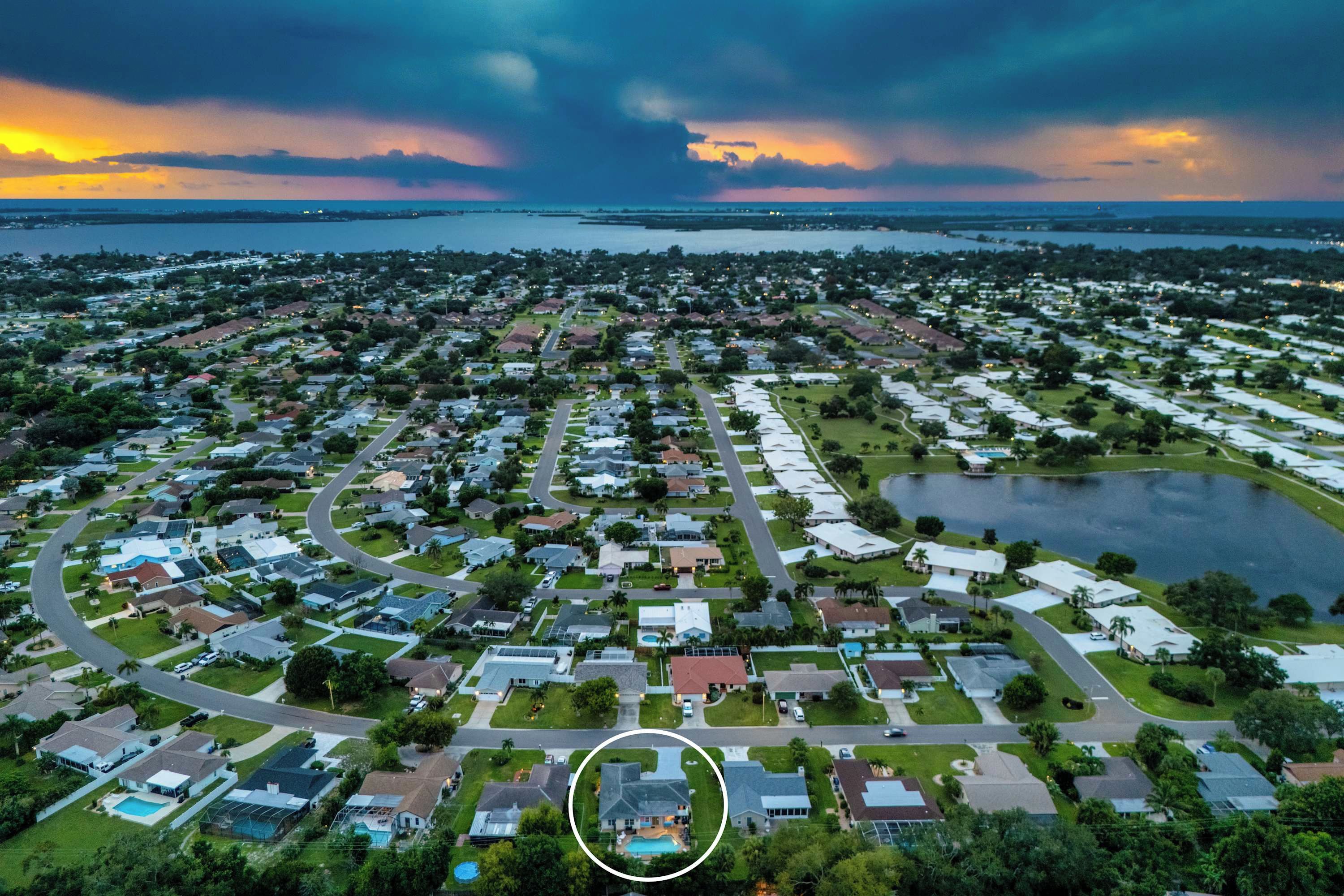 An aerial view of a residential area with houses, roads, and a body of water.