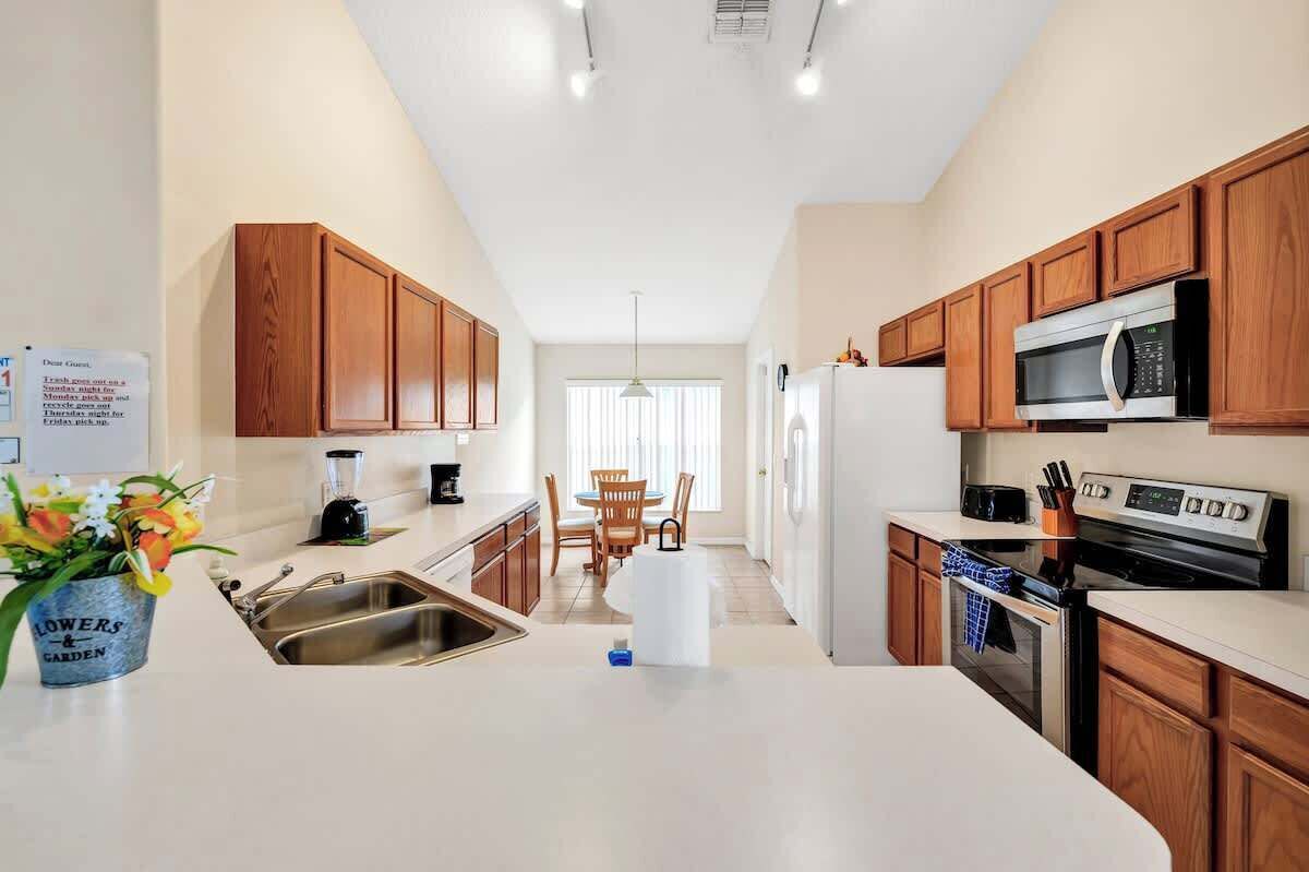 A modern kitchen with wooden cabinets, a built-in microwave, a stove, and a sink.