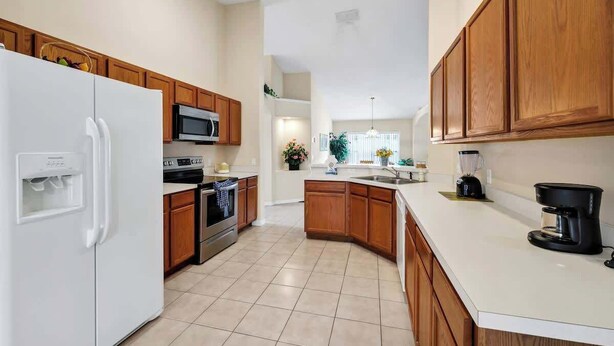 Una cocina moderna con armarios de madera, un refrigerador blanco, un microondas, un horno y una cafetera.
