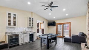 Una cucina moderna con un tavolo da calcio, una ventola a soffitto e una TV a parete.