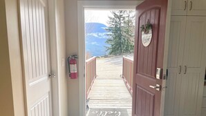 Una terrazza in legno che conduce a una vista sulle montagne, un estintore e un cartello di benvenuto.