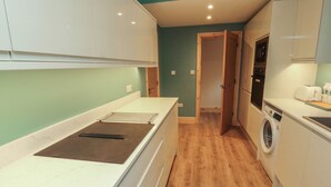 Een kleine keuken met een inbouwoven, een wasmachine en een klein aanrecht.