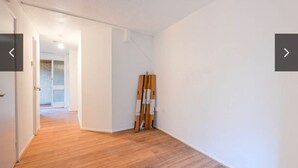 Un pasillo con suelo de madera y paredes blancas que conduce a una puerta.