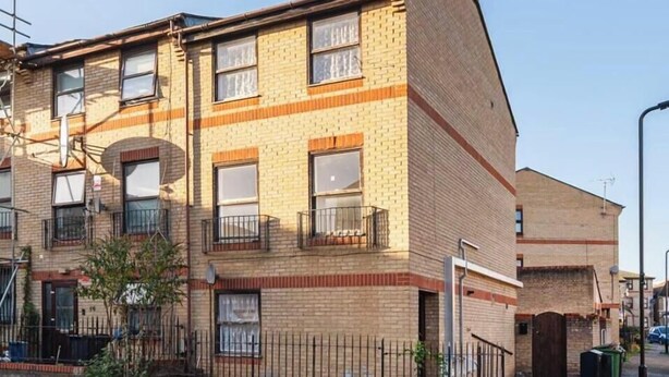 Un edificio residencial de varios pisos con fachada de ladrillo, múltiples ventanas y balcones.