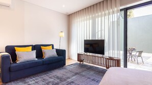 Una habitación moderna con sofá, televisión y balcón con mesa y sillas.