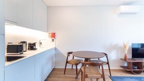A modern kitchen with a Bosch coffee maker, a sink, and a dining area with a round table and wicker chairs. - 1T | Rosário 244 by LovelyStay (Porto)