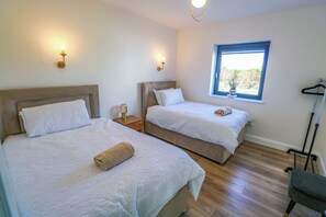 A hotel room with two beds, a window with a view, a hanging light fixture, and a floor lamp. - AN TOBAR, family friendly, with a garden in Belmullet, County Mayo (Ballina)