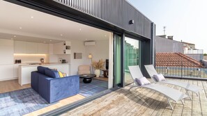 Een modern appartement met een zithoek, keuken en balkon met lounge fauteuils.