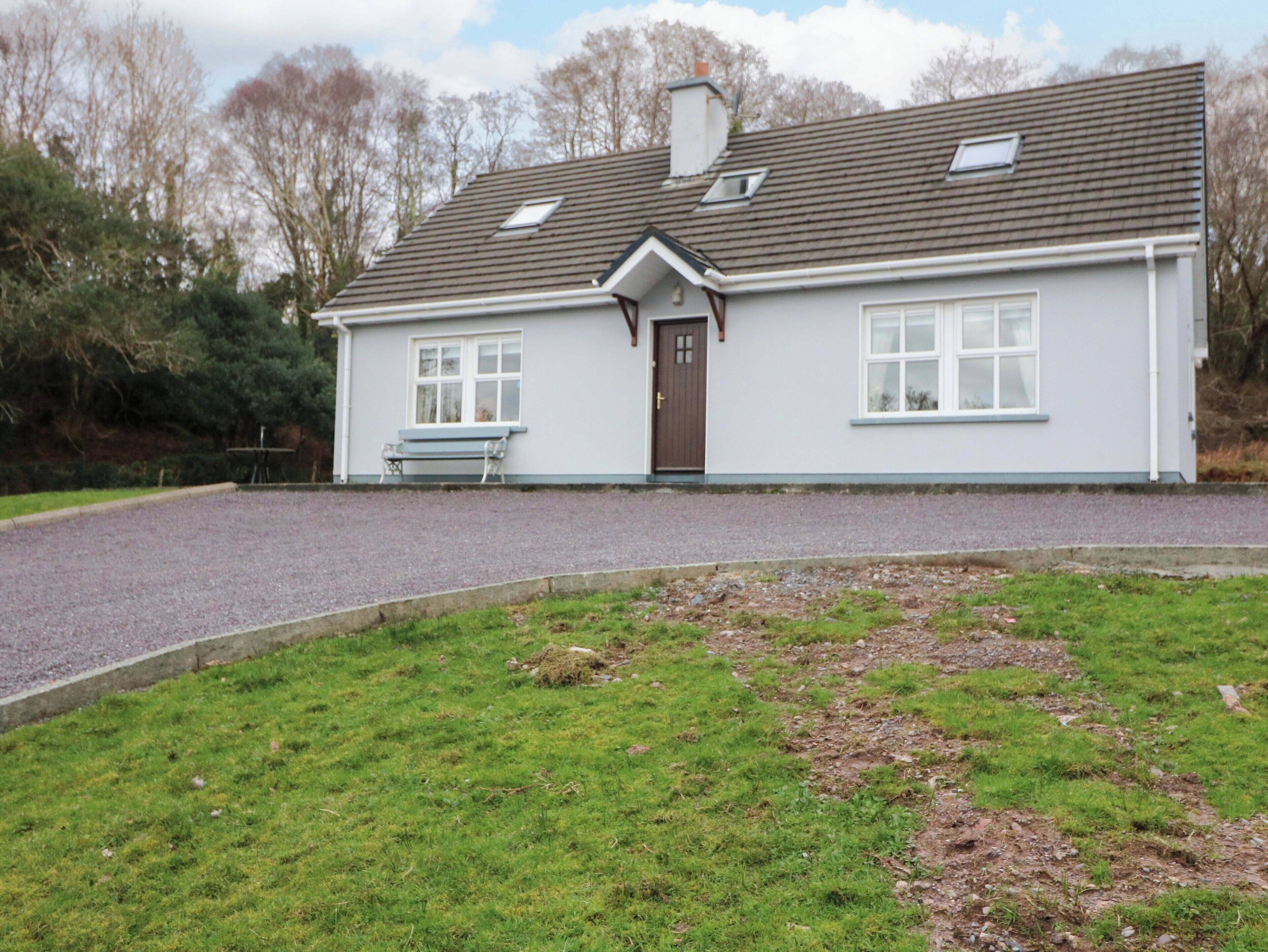 A single-story house with a gravel driveway, a front bench, and a door.