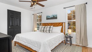 A bedroom with a bed, a ceiling fan, a window with curtains, and a door. - Cute Condo | Hot Tub | Minutes to Pigeon Forge! (Sevierville)