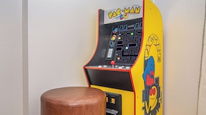 Máquina de arcade Pac-Man com um banquinho castanho na frente.