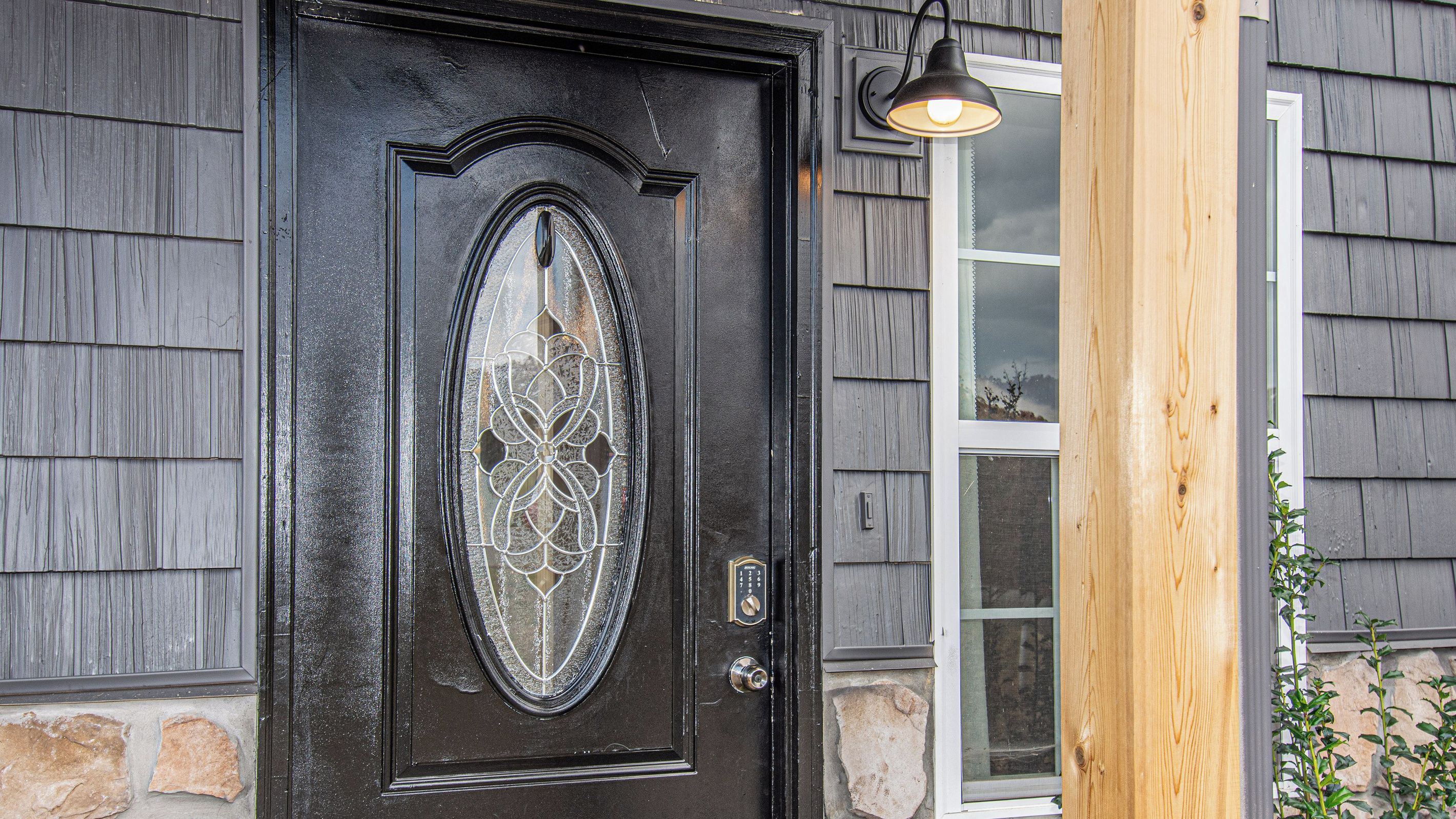 A black door with a decorative glass panel and a metal lock.
