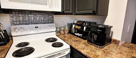 Una cocina con un horno blanco Frigidaire, un fabricante de café Keurig y un microondas.
