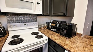 A kitchen with a white Frigidaire stove, a Keurig coffee maker, and a microwave. - Cute Condo | Hot Tub | Minutes to Pigeon Forge! (Sevierville)