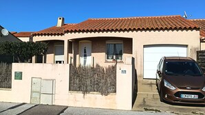 Ein Wohngebäude mit Ziegeldach, Garage und einem abgestellten Auto.