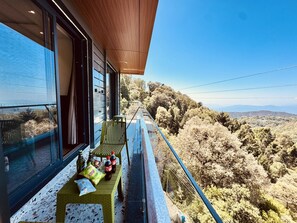 Un balcon avec une table où sont disposés des en-cas et des boissons, donnant sur un paysage montagneux.