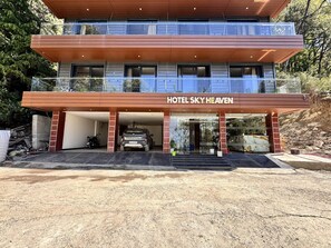 Um hotel moderno com estrutura em dois andares, entrada coberta e um carro visível na área de estacionamento.