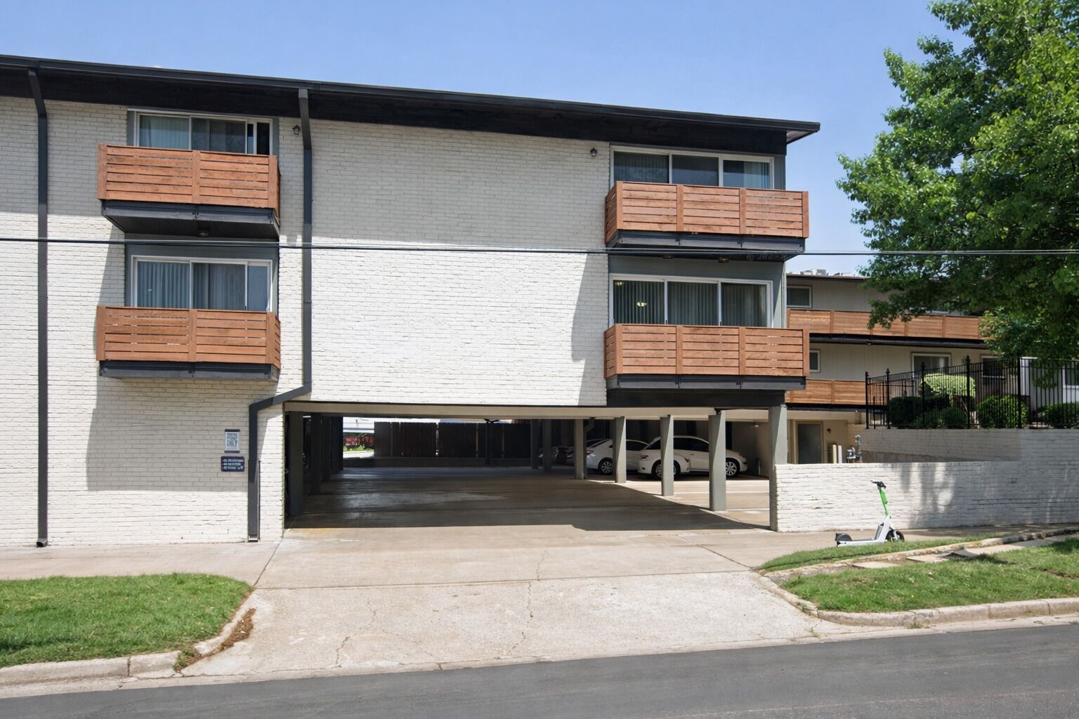 Un edificio de varios pisos con garaje, balcones de madera y cielo despejado.
