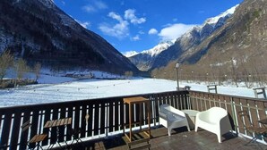 A deck with outdoor seating, overlooking a snowy valley and mountains. - Albergo Ristorante Casa Corti (Valbondione)
