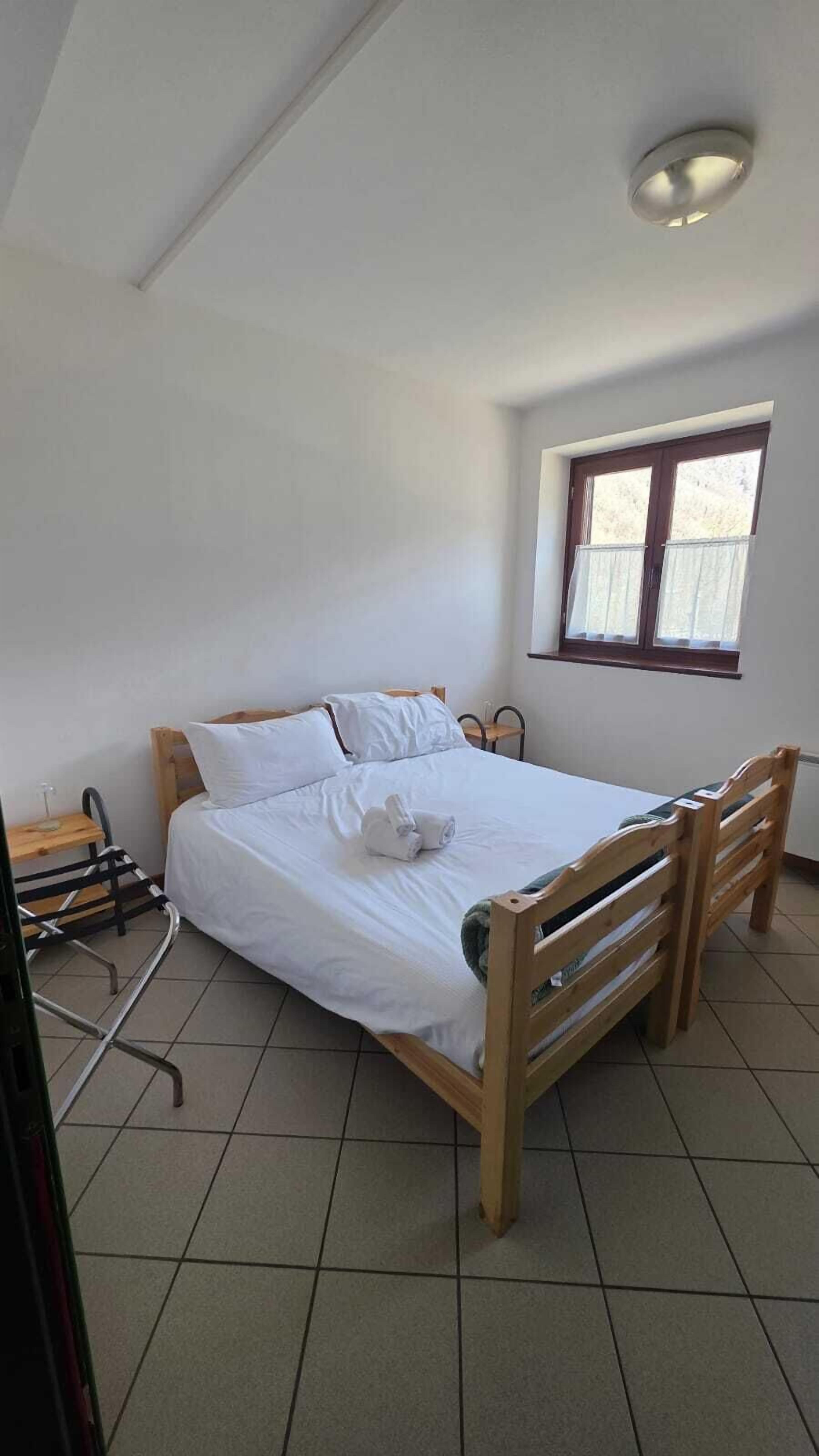 A bedroom with a bed, a window, a chair, and a small table.