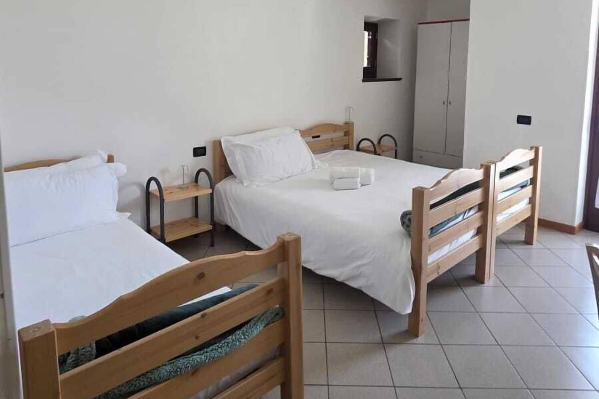 A room with two wooden beds, a white ceiling, and a tiled floor.