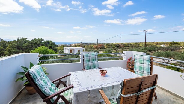 A balcony with a table, chairs, and a view of the landscape.