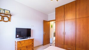 A bedroom with a bed, a dresser, a television, and wooden wardrobes.