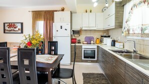 A compact kitchen with a dining area, a refrigerator, an oven, and a sink.
