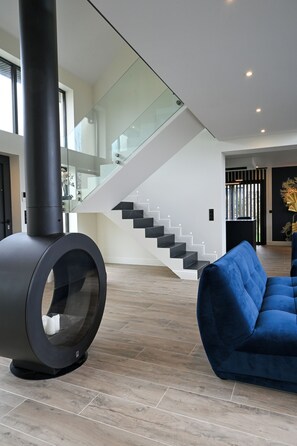 Un interior moderno con un objeto cilíndrico negro, un sofá azul y una escalera.