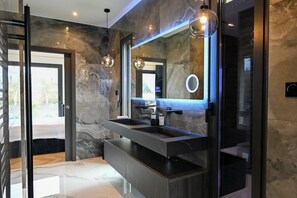 Une salle de bain moderne avec un grand miroir, deux lavabos et une douche à l’italienne.