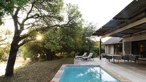 A swimming pool with lounge chairs and a dining area, surrounded by trees. - Villa Riviersig,  a new stylish bushvilla (Hoedspruit)