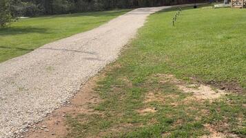 A gravel path leading through a grassy area with trees on both sides.