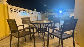 An outdoor patio with a round table and four chairs, surrounded by a white decorative fence. - Elegant Studio good for relaxing and work. (Sint Michiel)