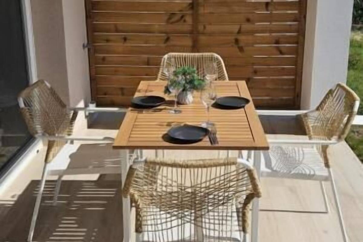 A dining area with a wooden table, wicker chairs, and a hanging light fixture.