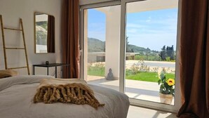 A bedroom with a bed, a window, a ladder, and a view of the outdoors. - Arillas Peaceful Bungalows (Corfu)