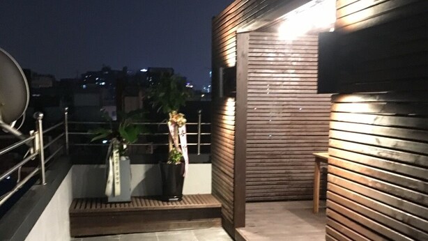 A rooftop terrace with a wooden wall, a small table, and a potted plant.
