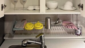 A kitchen with white cabinets, clear glassware, and a sink area with a dish rack.