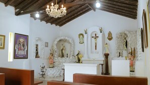 A church interior with pews, a chandelier, statues, and religious icons.