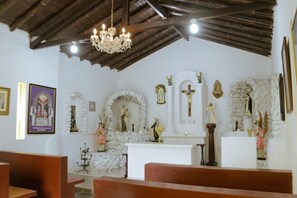 Interior de igreja com bancos, lustre, estátuas e ícones religiosos.