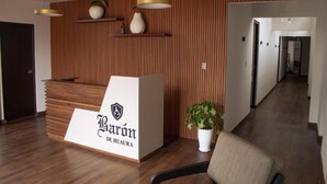 A reception desk with a logo, a wooden wall with vertical slats, and a potted plant.