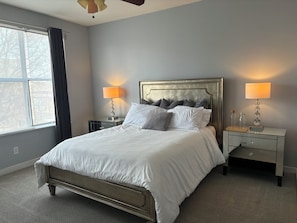 A bedroom with a bed, two bedside tables, a nightstand, a window with curtains, and a ceiling fan. - 4 Story Roof Top Loft & Mercedes Stadium View, Walk to FIFA World Cup (Atlanta)