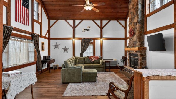 A cozy room with a fireplace, wooden beams, and a television.