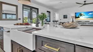 Een moderne keuken met een groot eiland, roestvrijstalen apparatuur en een hanglamp.