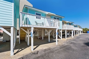 A row of beach houses with balconies, a covered parking area, and a clear blue sky. - ๐ถPet Friendly | Community Pool + Walk to Beach | Sea and Sun Unit 2๐๐ (Gulf Shores)