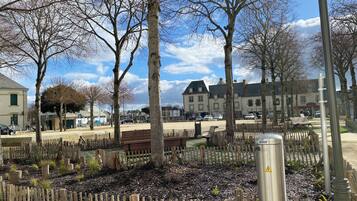 Un parc avec des bancs, des arbres et un bâtiment en arrière-plan.