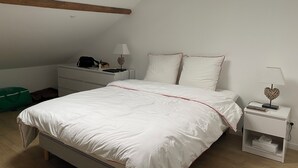 Une chambre à coucher avec un lit, des tables de chevet, un bureau et un sac vert.