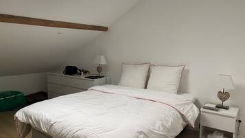 Une chambre à coucher avec un lit, des tables de chevet, un bureau et un sac vert.