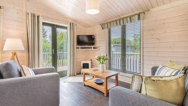 Een gezellige kamer met een bank, een houten salontafel, een televisie en een raam met zonwering.